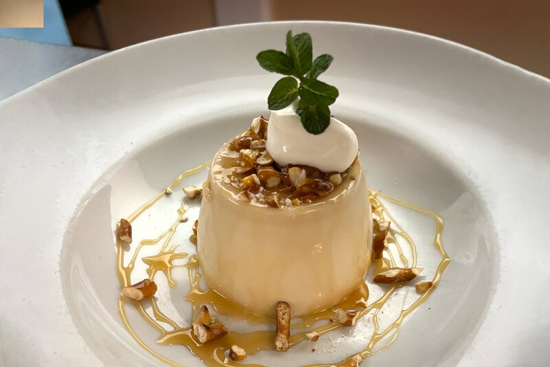 Ice cream dessert topped with nuts, caramel and cream